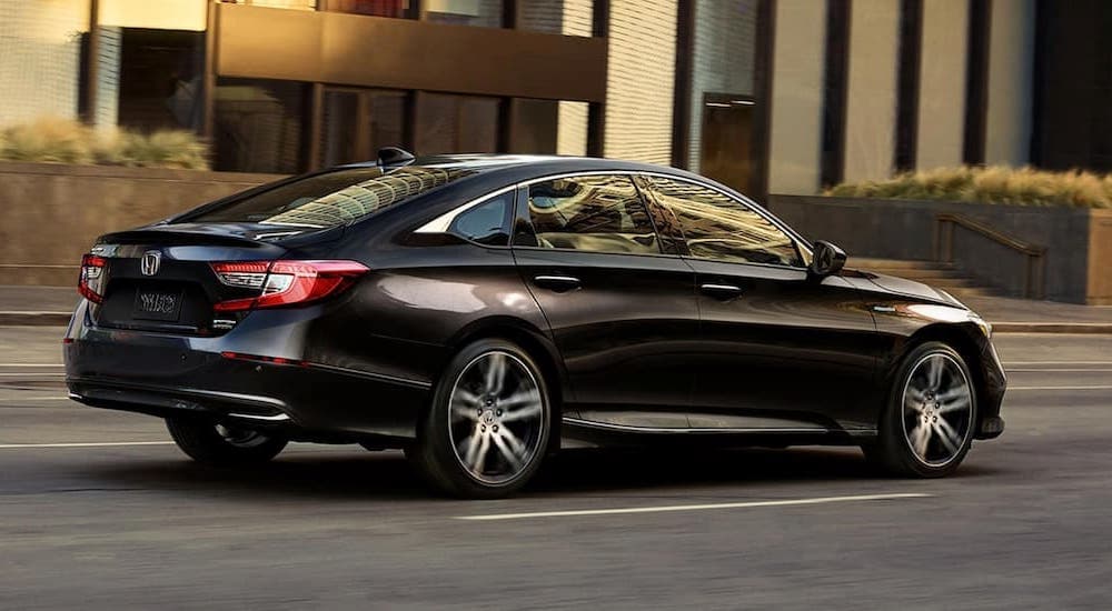 A black 2022 Honda Accord is shown from a rear angle driving on a city street.