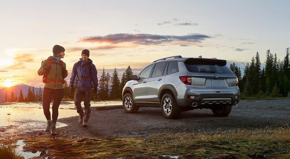 A silver 2022 Honda Passport Trailsport is shown from the rear next to a hiking trail.