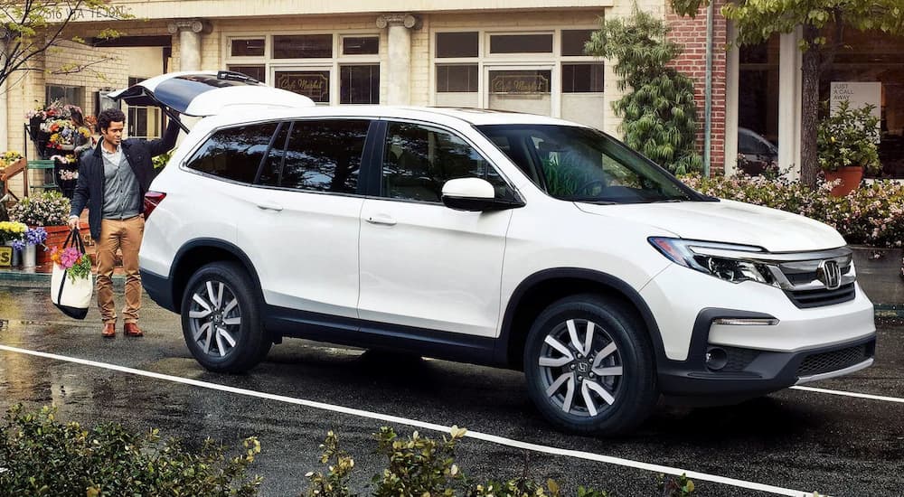 A white 2022 Honda Pilot EX-L is shown parked outside of a storefront.