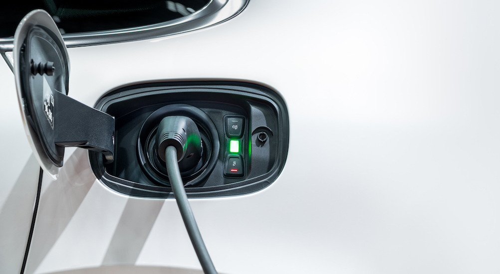 A close up of an EV charging port on a white vehicle is shown.