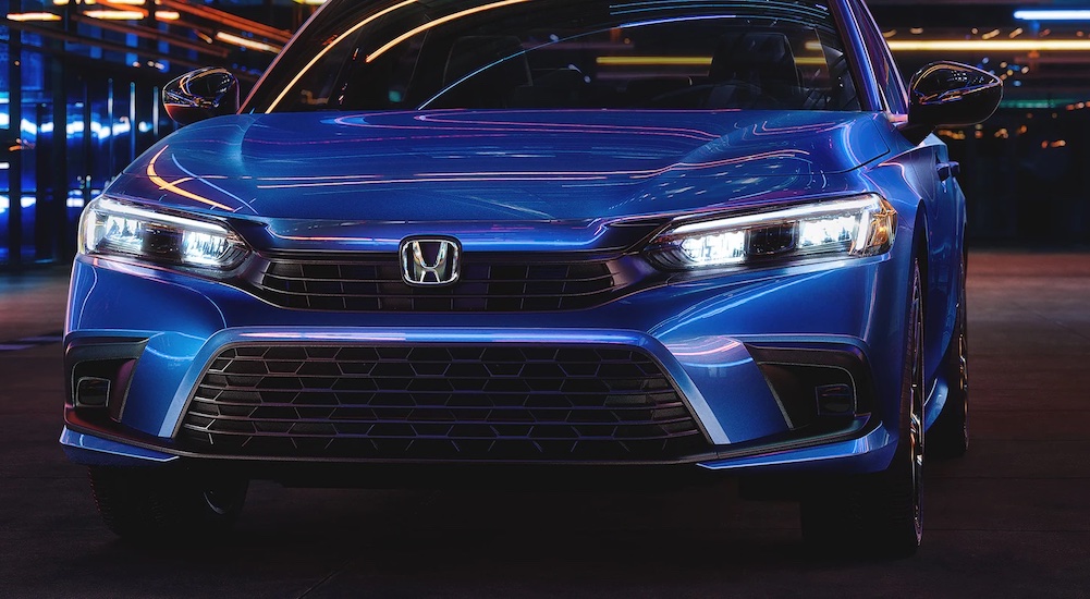 A close up of the front of a blue 2022 Honda Civic Sport is shown at night.