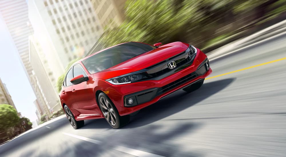 A popular used Honda for sale, a red 2019 Honda Accord, is shown driving through a city.
