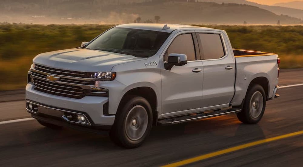 A white 2019 Chevy Silverado 1500 is shown driving on an open road after viewing used trucks for sale.
