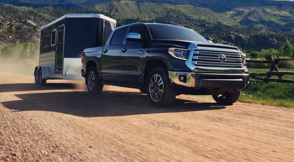 A black 2020 Toyota Tundra is shown towing a black enclosed trailer on a dirt road.